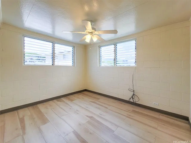 an empty room with wooden floor chandelier fan and windows