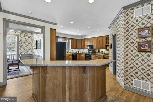 a kitchen with stainless steel appliances granite countertop a refrigerator a sink dishwasher a stove and white countertops with wooden floor