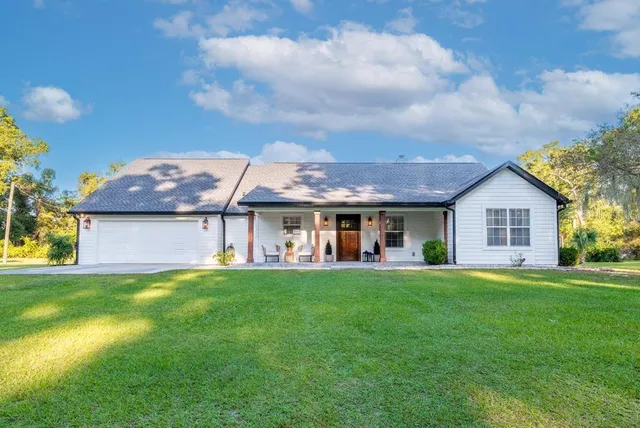 a view of a house with a big yard and large trees