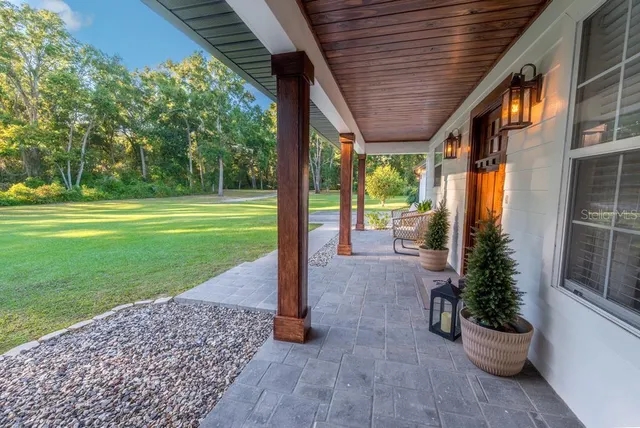 a view of a patio with table and chairs potted plants with wooden floor and fence