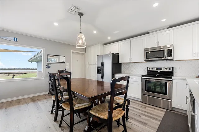 a kitchen with stainless steel appliances a dining table chairs stove refrigerator and microwave