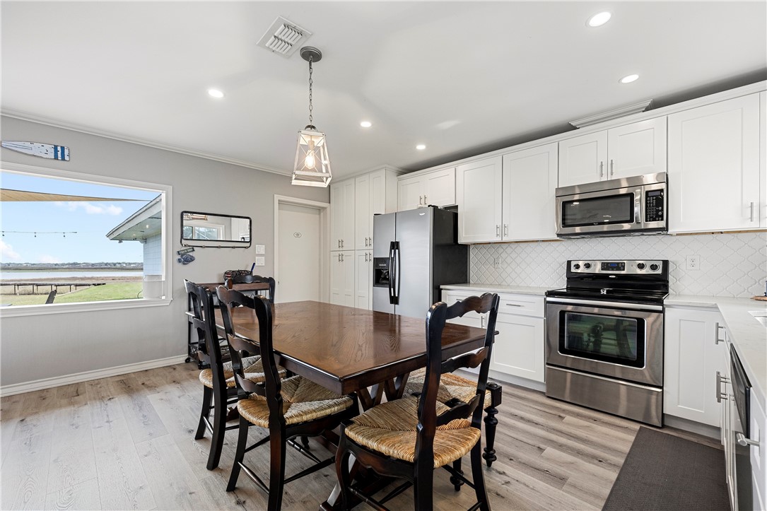 140 Zenna Drive Mathis, TX 78368 - Photo 12 of 31 a kitchen with stainless steel appliances a dining table chairs stove refrigerator and microwave