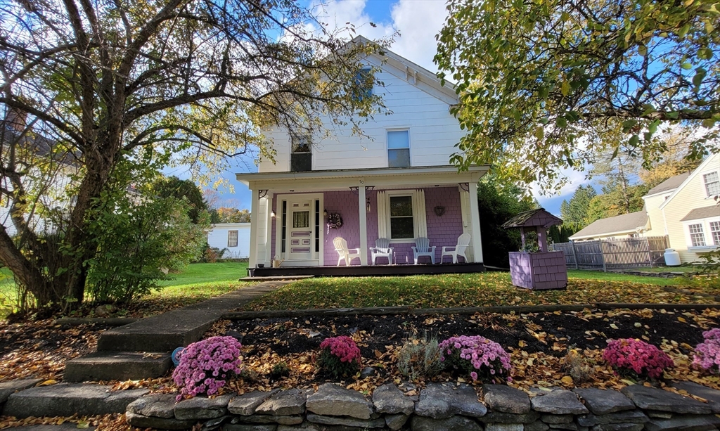 a front view of a house with a garden and trees