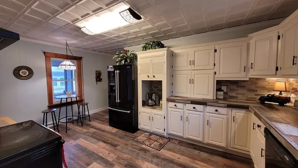 a kitchen with stainless steel appliances granite countertop a sink a stove a refrigerator cabinets and a dining table