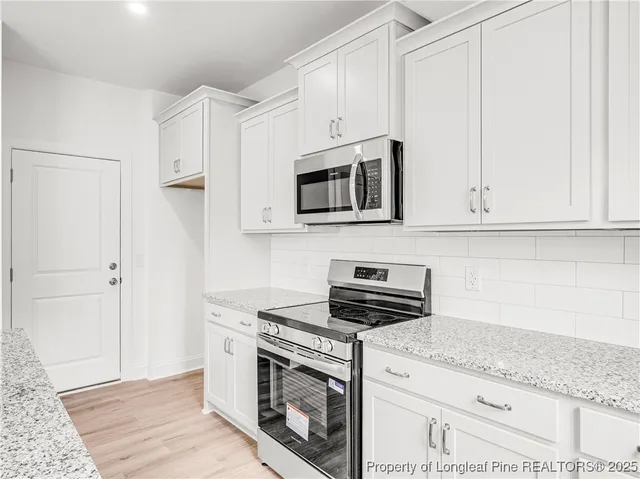 a kitchen with stainless steel appliances granite countertop white cabinets and white stove top oven with granite countertops