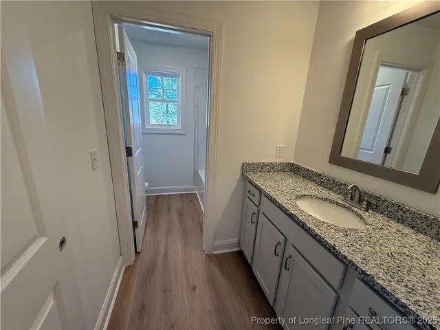 a bathroom with a granite countertop sink and mirror with toilet