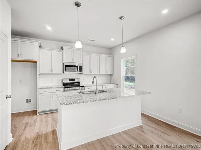 a kitchen with kitchen island a sink a stove a refrigerator and white cabinets