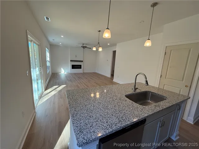 a kitchen with granite countertop a sink a counter top space and cabinets