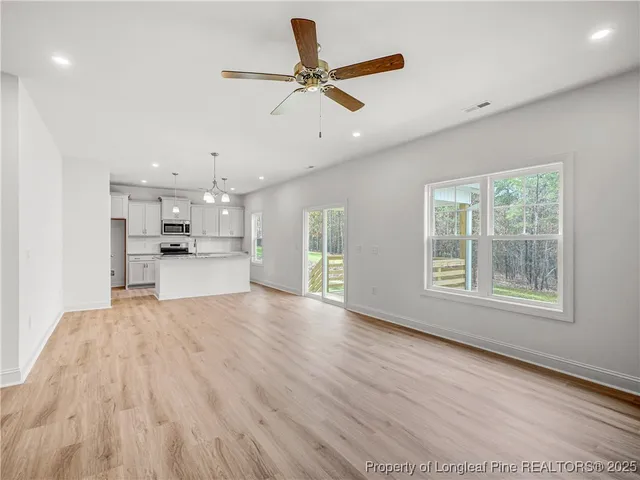 a view of an empty room with a window and kitchen view