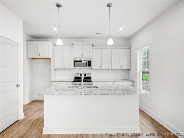 a kitchen with kitchen island granite countertop a sink a center island a counter space and cabinets