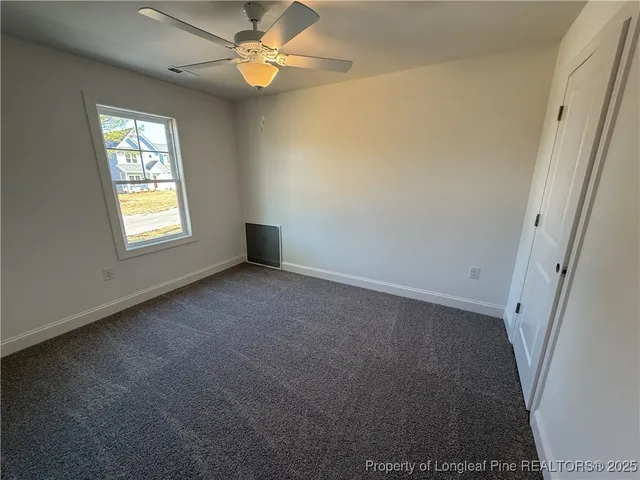 an empty room with windows and fan
