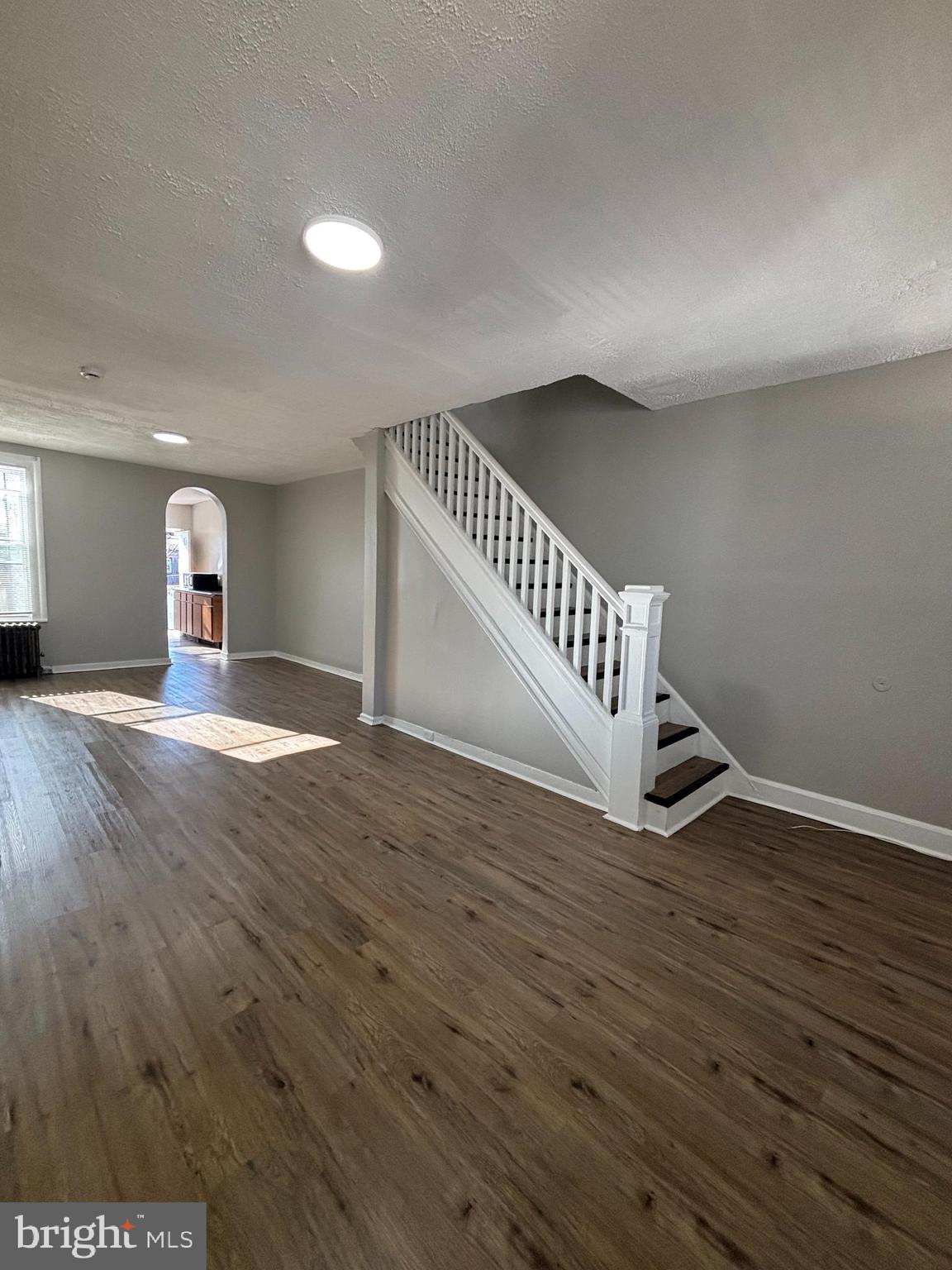 a view of an empty room with wooden floor and staircase