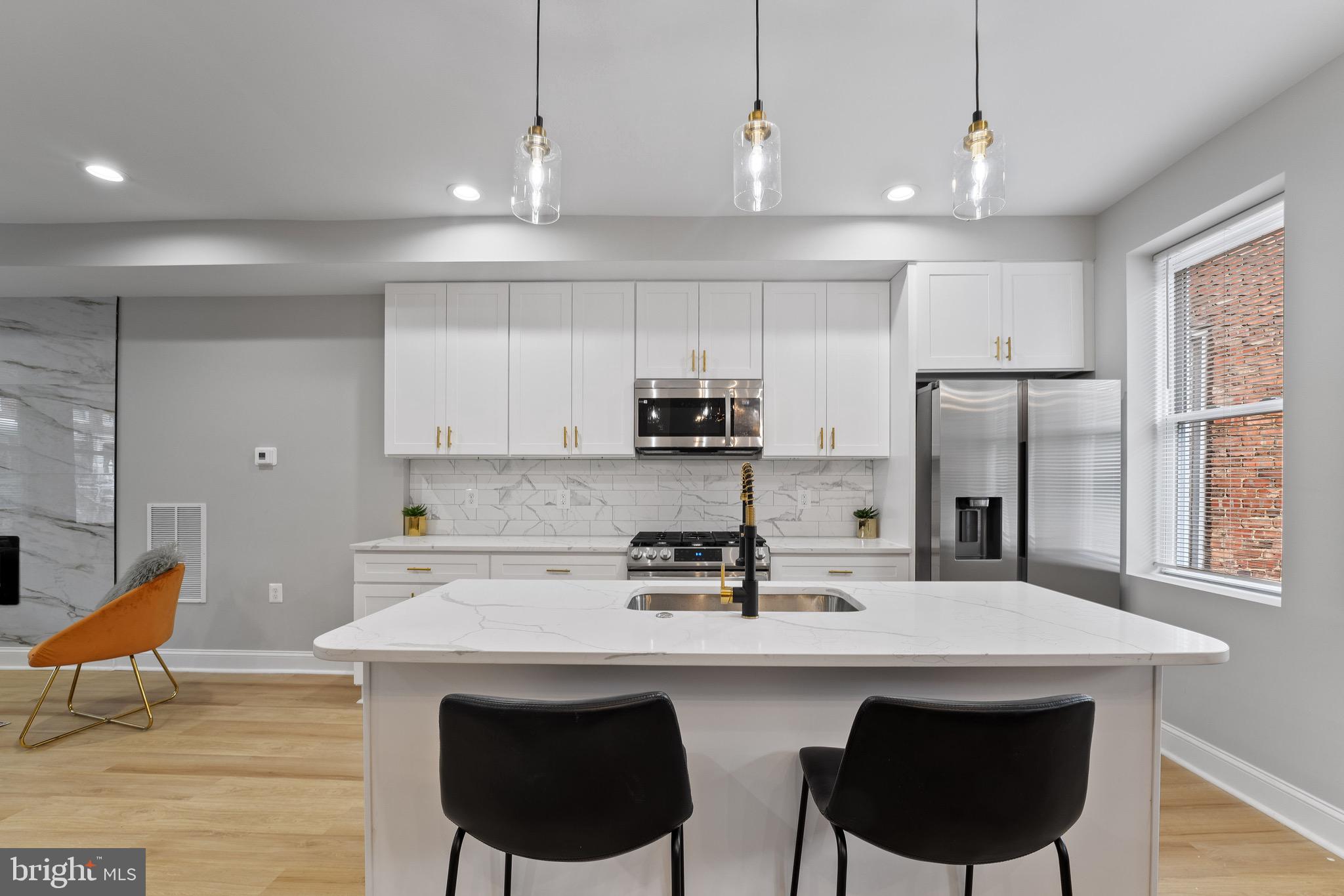 655 Dumbarton Avenue Baltimore, MD 21218 - Photo 3 of 28 a kitchen with stainless steel appliances granite countertop a sink a stove a refrigerator and white cabinets with wooden floor