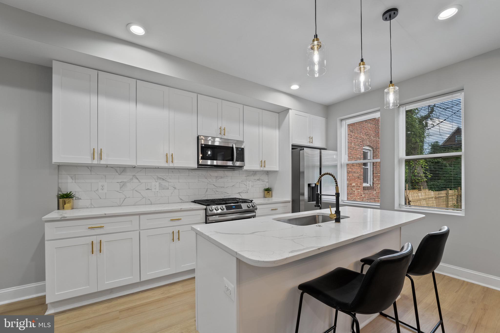 655 Dumbarton Avenue Baltimore, MD 21218 - Photo 4 of 28 a kitchen with stainless steel appliances kitchen island a white table chairs and a refrigerator