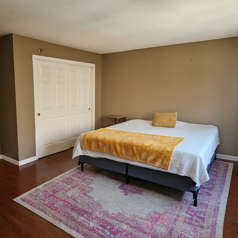 124 Tennis Plaza Road, Unit 22 Dracut, MA 01826 - Photo 4 of 9 a bedroom with a bed and wooden floor