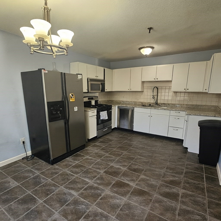 124 Tennis Plaza Road, Unit 22 Dracut, MA 01826 - Photo 6 of 9 a kitchen with stainless steel appliances a refrigerator a sink a stove a microwave and cabinets