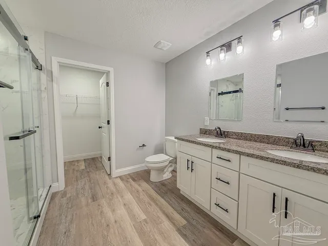 a spacious bathroom with a granite countertop sink a toilet and a shower