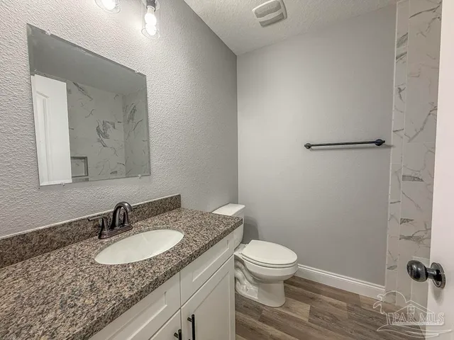a bathroom with a granite countertop sink toilet a mirror and shower