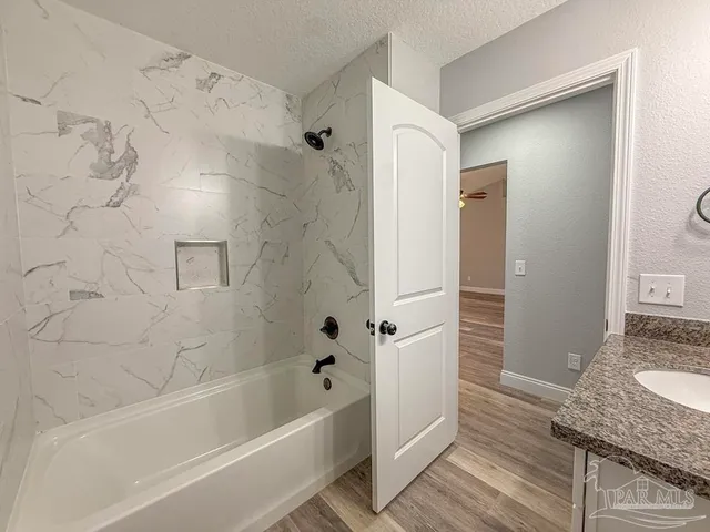 a bathroom with a granite countertop bathtub shower and sink