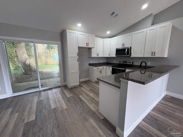 a kitchen with stainless steel appliances granite countertop a stove a sink and a microwave