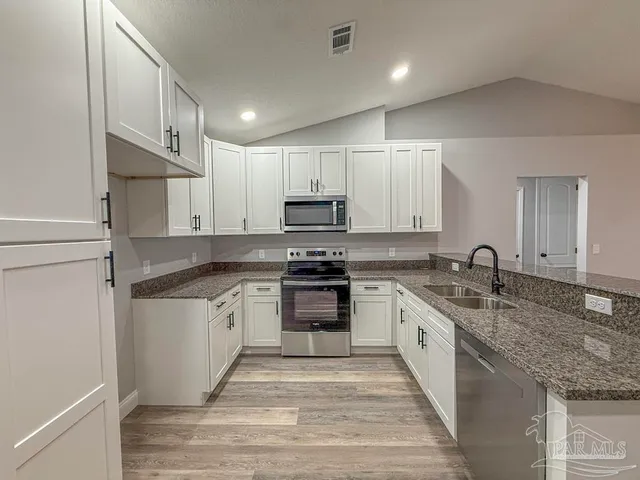 a kitchen with stainless steel appliances granite countertop a sink and dishwasher a stove top oven with wooden floor