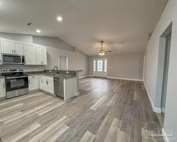a large kitchen with cabinets wooden floor and stainless steel appliances