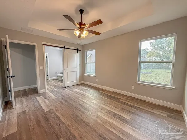 an empty room with wooden floor fan and windows