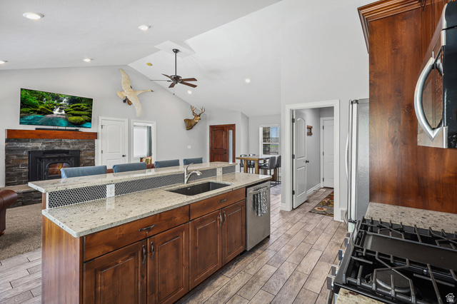 1588 West Rim Rock Drive Stockton, UT 84071 - Photo 14 of 61 Kitchen island featuring a stainless steel sink, granite countertops, and rich wood cabinetry