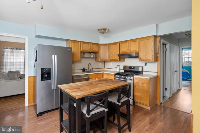 a kitchen with a refrigerator a stove a sink a dining table and chairs