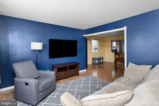 a living room with furniture a flat screen tv and kitchen view