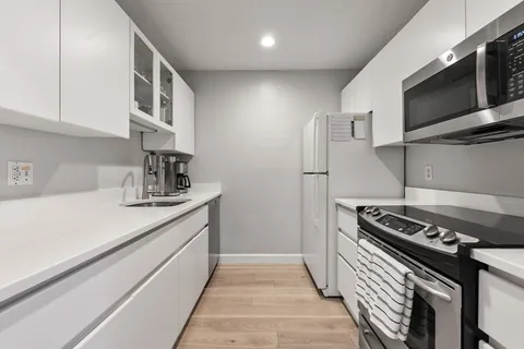 a kitchen with stainless steel appliances a sink dishwasher a stove and a microwave oven with cabinets