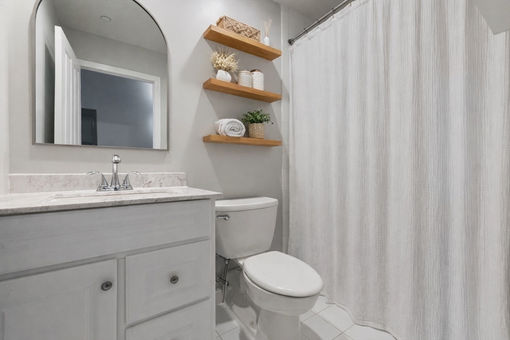 75 Clarendon Street, Unit 201 Boston, MA 02116 - Photo 8 of 12 a bathroom with a granite countertop sink a toilet and a mirror