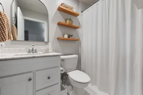 a bathroom with a granite countertop sink and a toilet