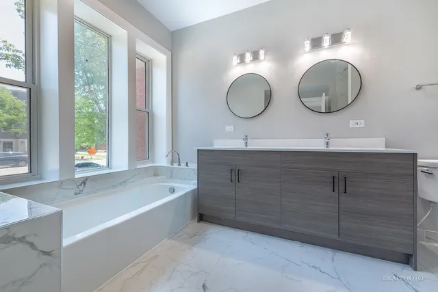 a bathroom with a double vanity sink mirror and bathtub