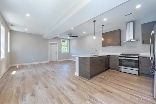 a large kitchen with stainless steel appliances a large counter top a stove and a wooden floors