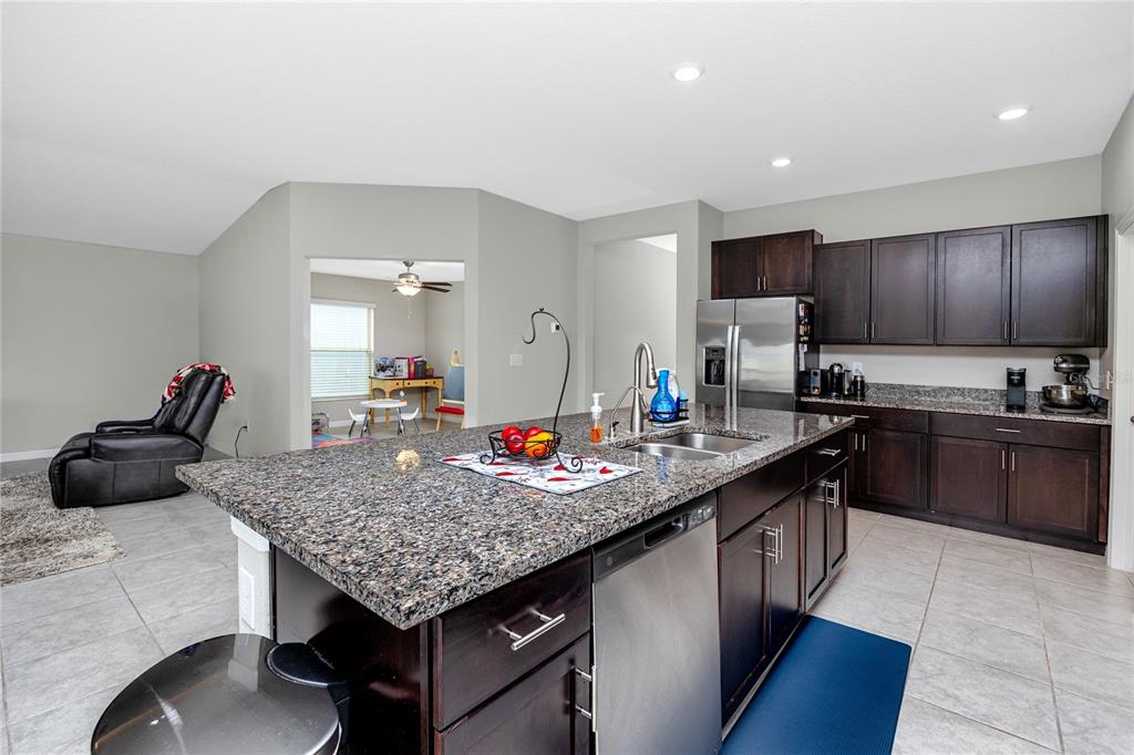 16654 Carlton Pond Street Wimauma, FL 33598 - Photo 15 of 48 a kitchen with granite countertop kitchen island stainless steel appliances a sink stove and refrigerator