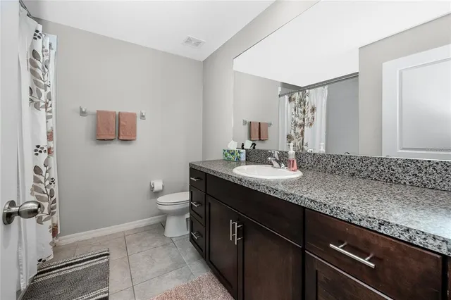 a bathroom with a granite countertop sink a toilet and mirror