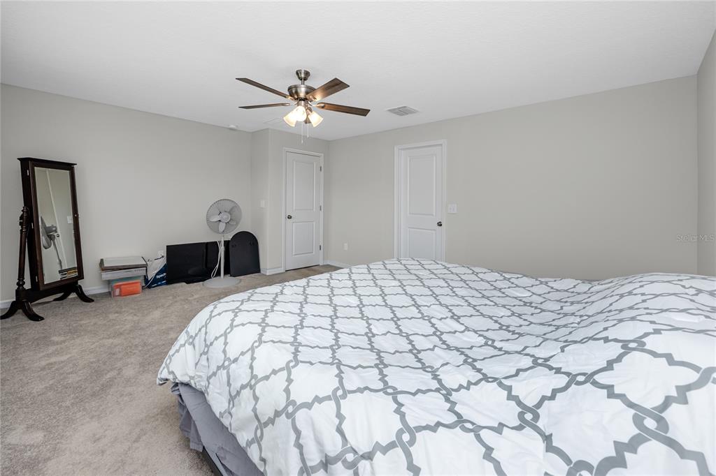 16654 Carlton Pond Street Wimauma, FL 33598 - Photo 29 of 48 a bedroom with a bed and a chandelier