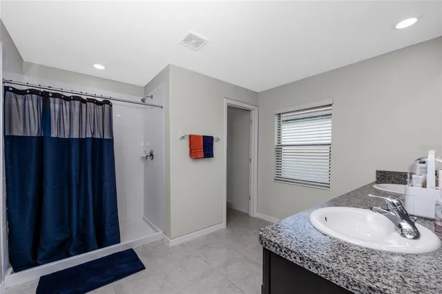 a bathroom with a granite countertop sink a mirror a vanity and shower