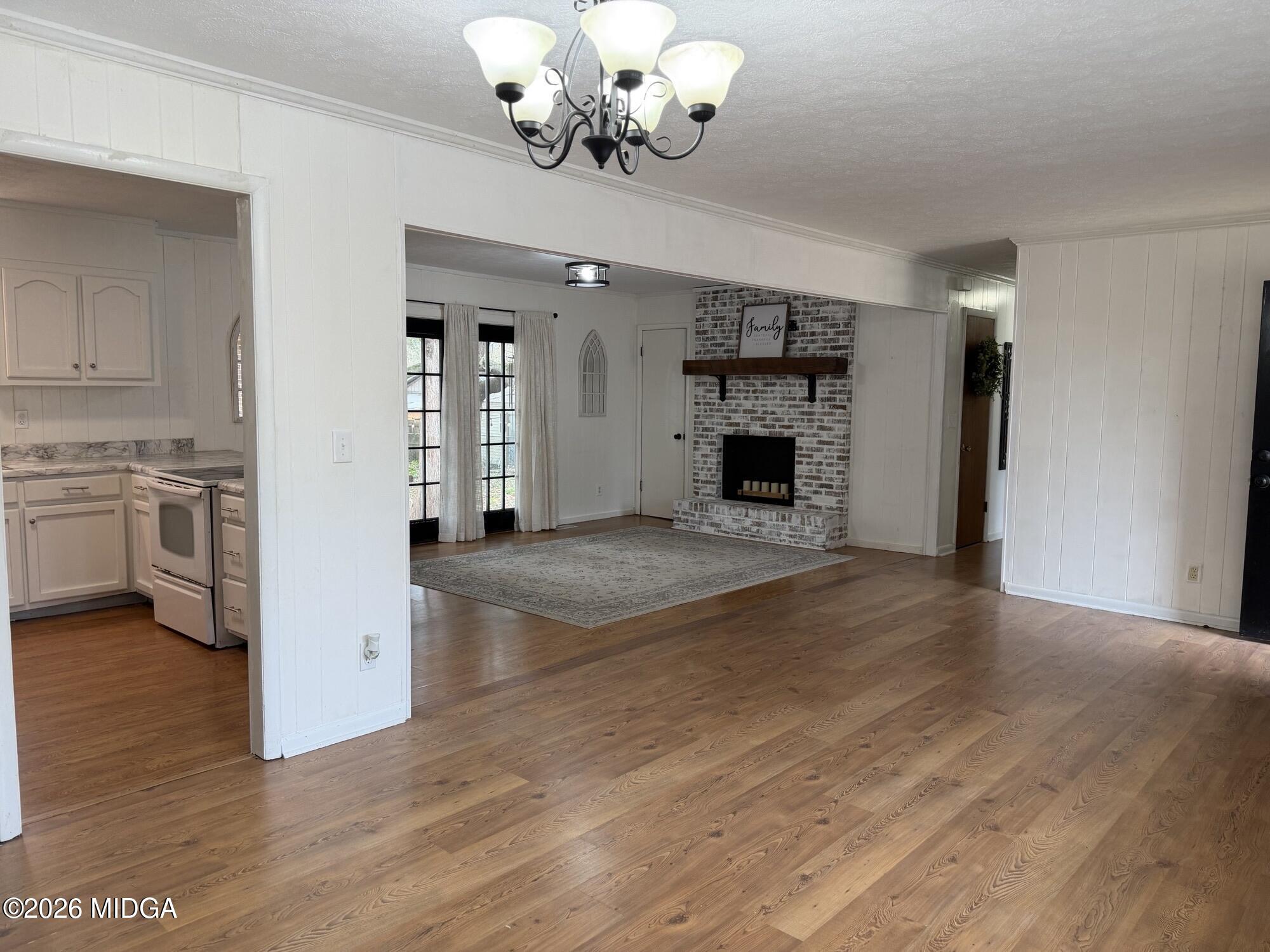 229 Southwest Peter Street Cochran, GA 31014 - Photo 2 of 24 an empty room with wooden floor fireplace and chandelier fans