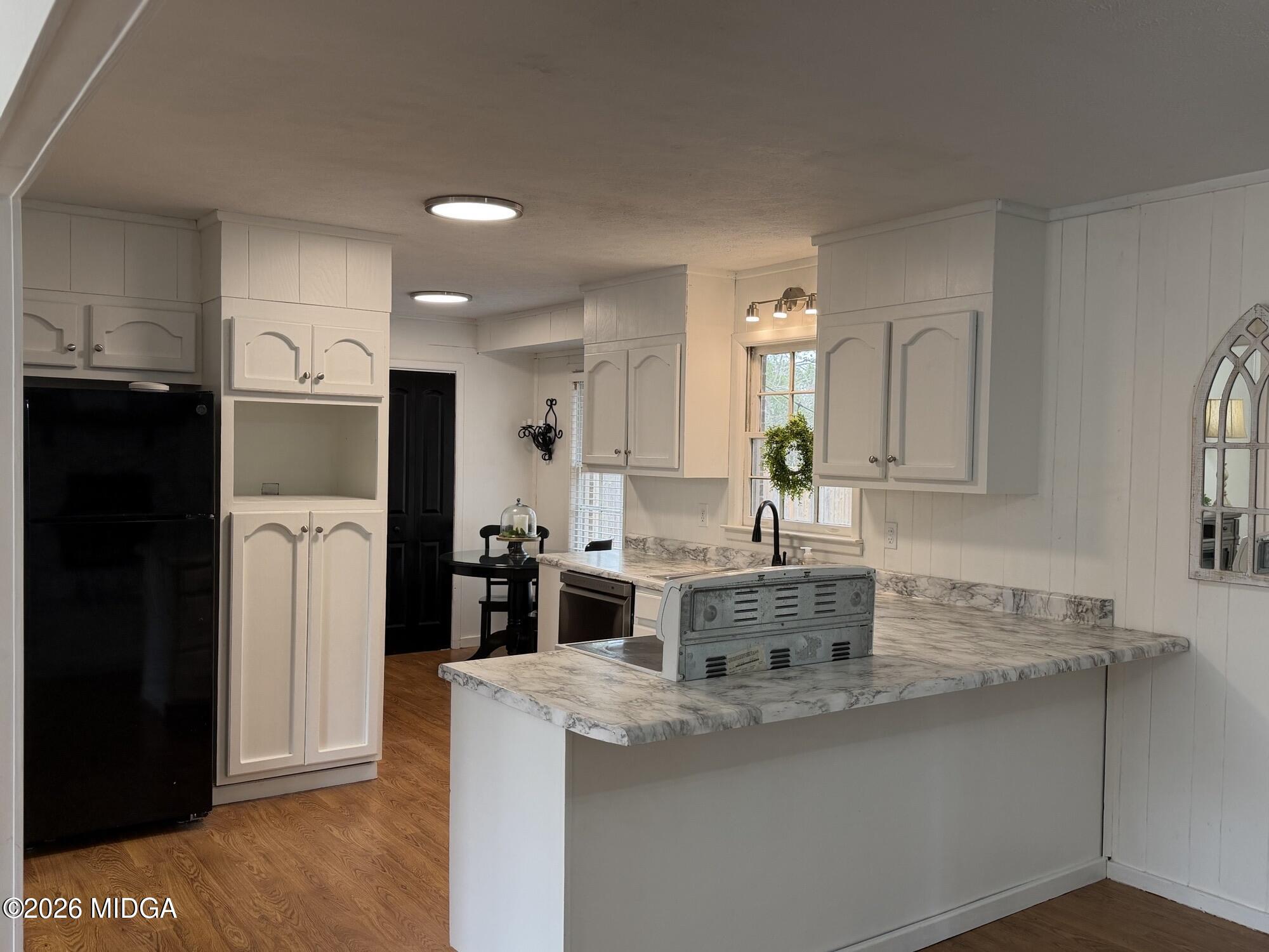 229 Southwest Peter Street Cochran, GA 31014 - Photo 5 of 24 a kitchen with stainless steel appliances granite countertop a refrigerator a sink a stove and white cabinets with wooden floor