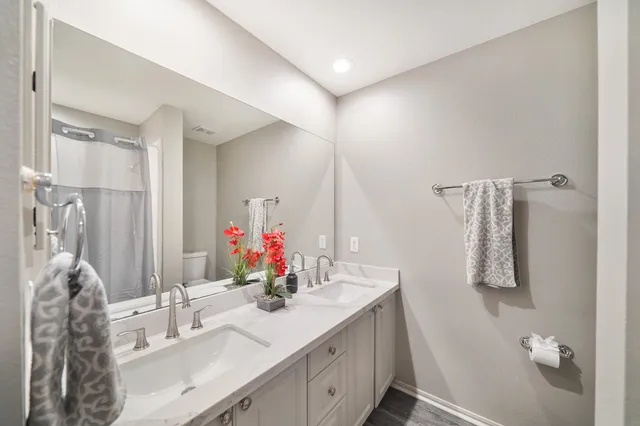 a bathroom with a double vanity sink mirror and shower