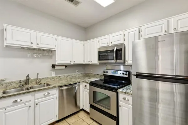 a kitchen with granite countertop a sink stove and white stainless steel appliances