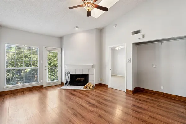 an empty room with wooden floor fireplace and windows