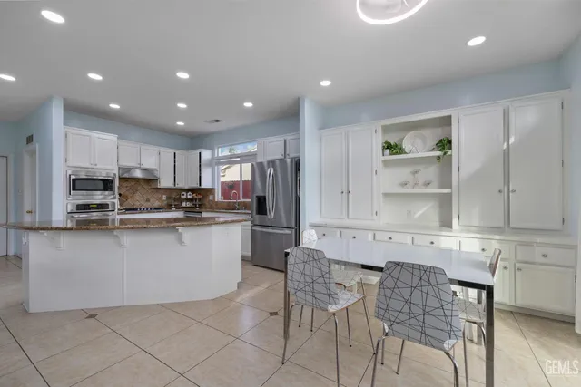 a kitchen with stainless steel appliances granite countertop a stove top oven a sink and white cabinets