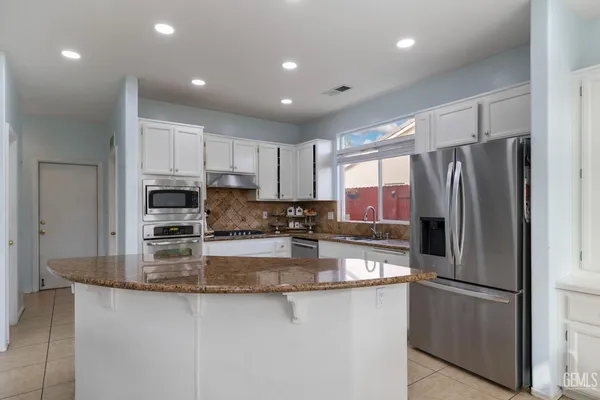 a kitchen with stainless steel appliances granite countertop a refrigerator a stove a sink and a granite counter tops