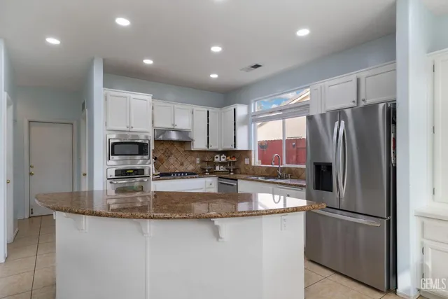 a kitchen with stainless steel appliances granite countertop a refrigerator a stove a sink and a granite counter tops