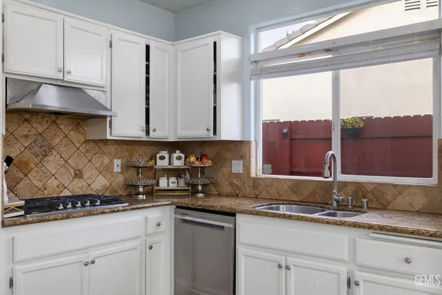 a kitchen with stainless steel appliances granite countertop a sink a stove and a granite counter tops with white cabinets