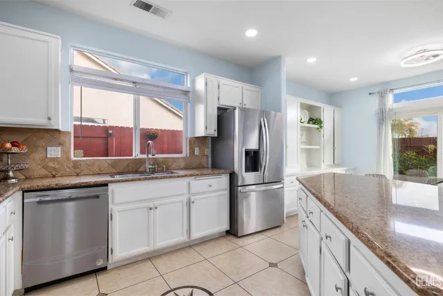 a kitchen with granite countertop a sink stainless steel appliances and window