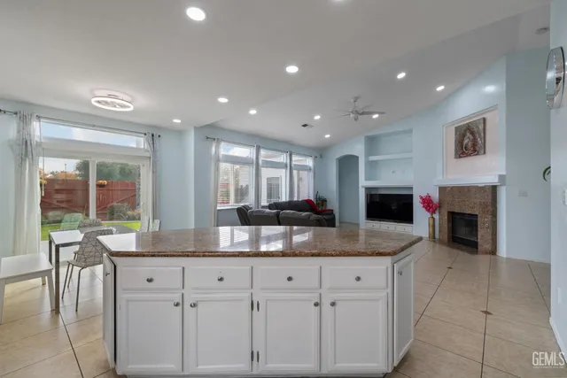 a kitchen with kitchen island granite countertop a sink a counter top space and cabinets